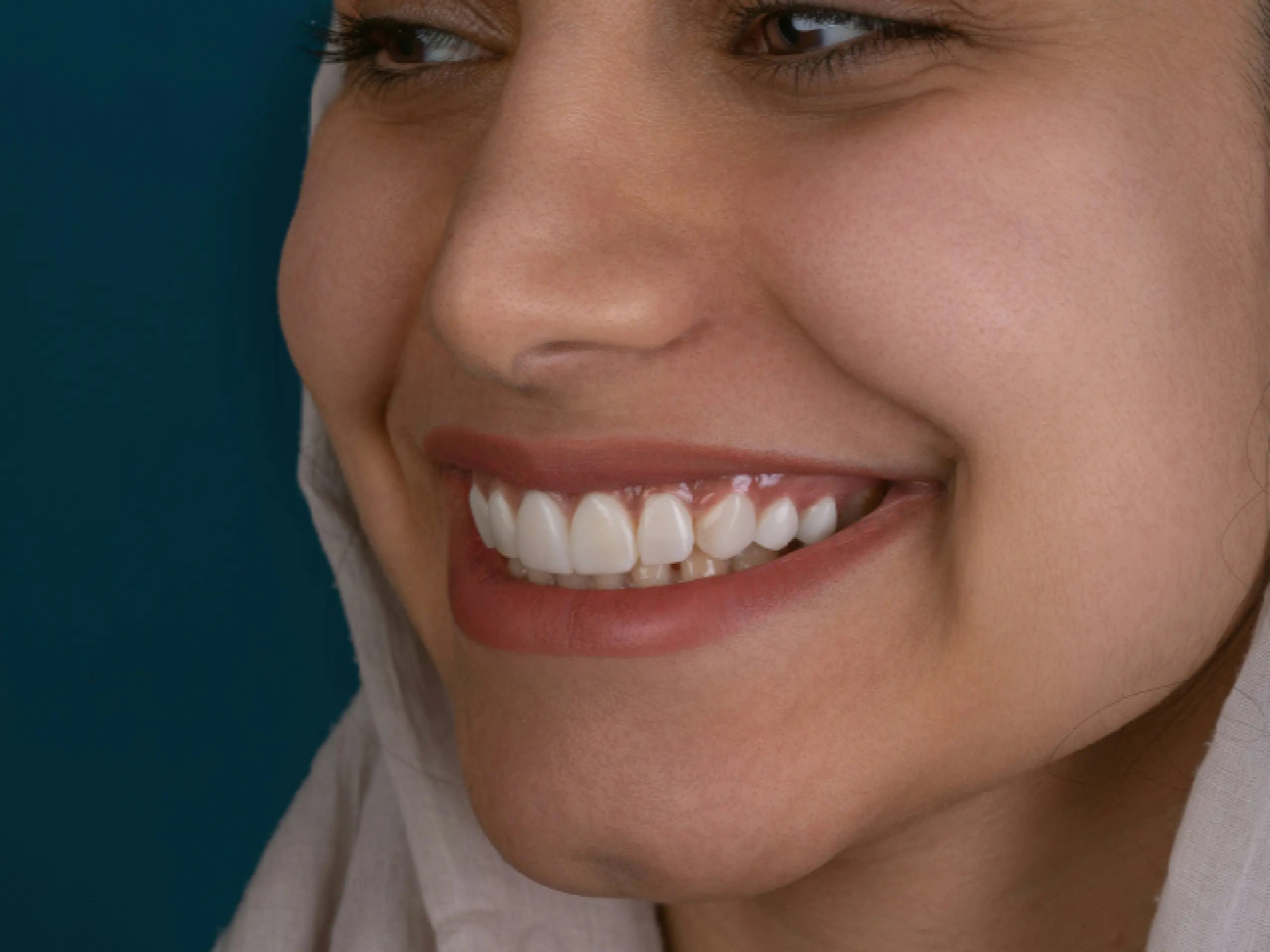 Primer plano de perfil de una mujer joven sonriendo, mostrando unos dientes blancos y alineados.