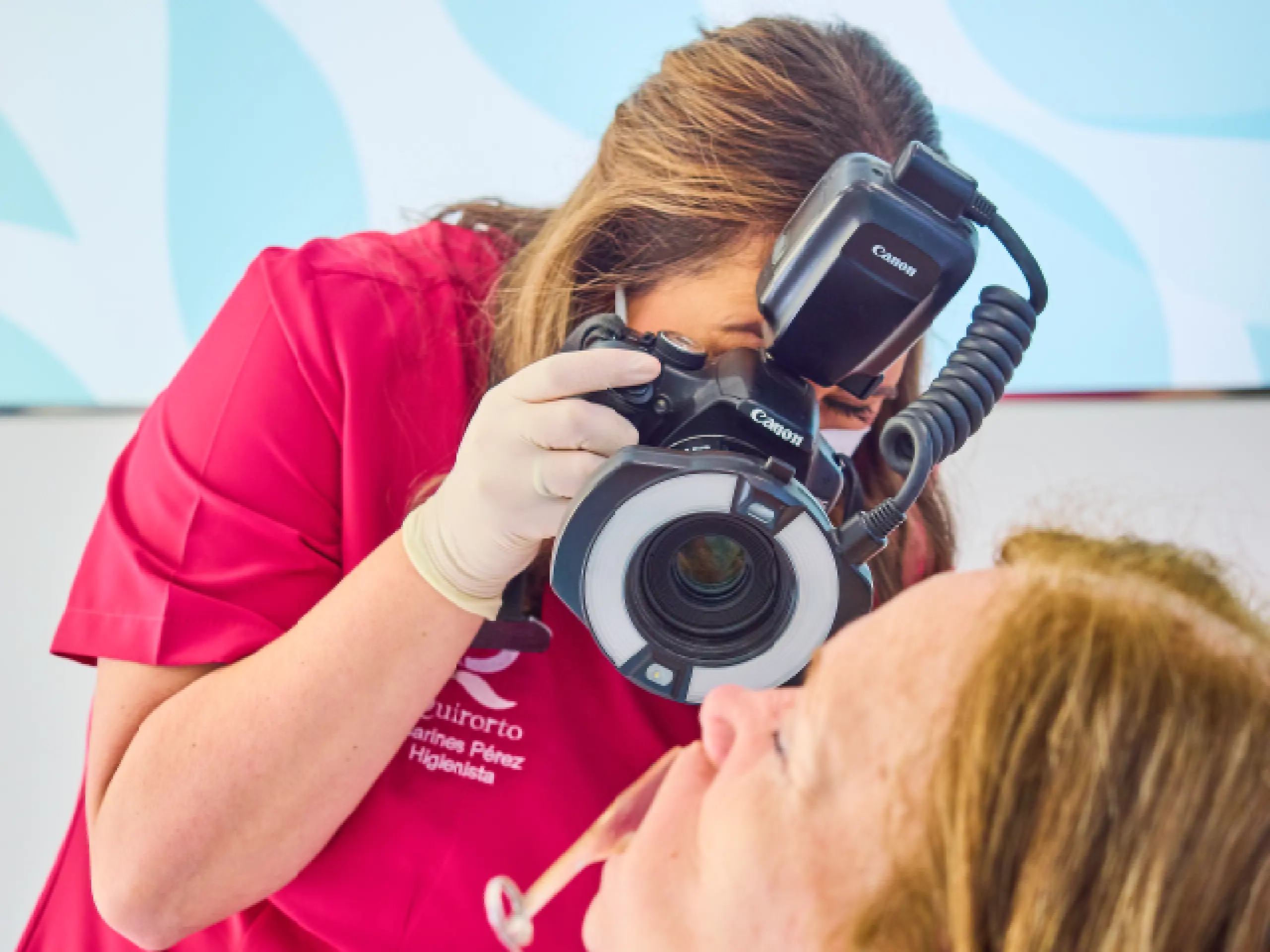 Higienista dental o fotógrafa médica tomando una foto intraoral de la boca de un paciente con una cámara Canon equipada con un flash anular.
