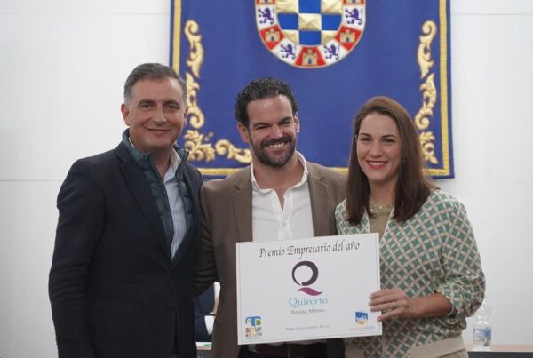Tres personas (dos hombres y una mujer) posan sonriendo mientras sostienen el certificado del "Premio Empresario del Año" otorgado a Quirorto Batista Moreno, con un escudo institucional de fondo azul.